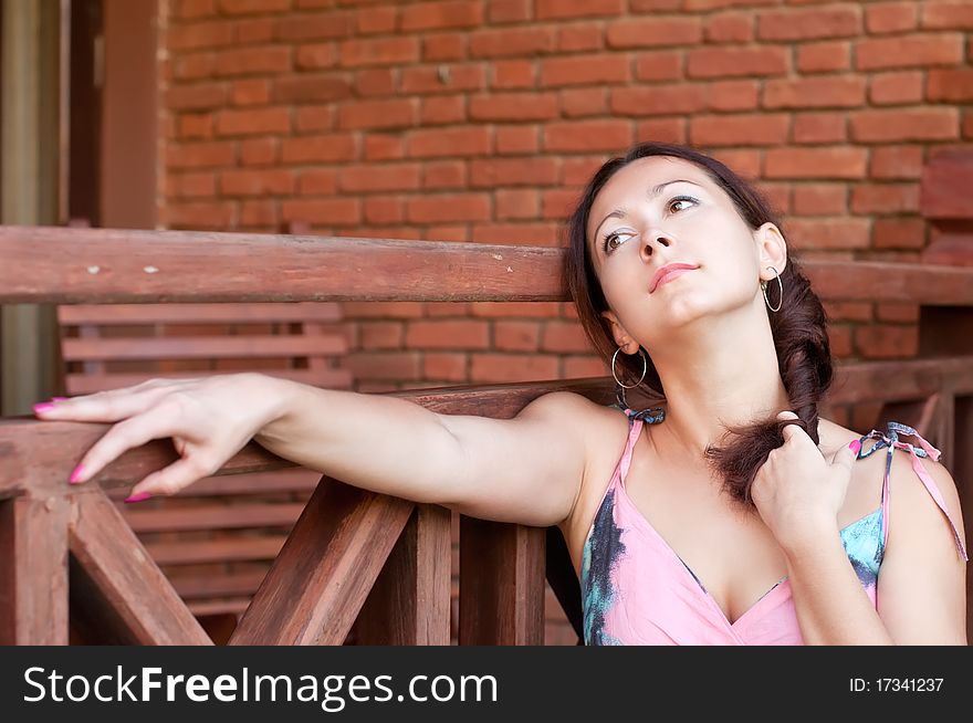 Young beautiful woman is dreaming near the brick wall. Young beautiful woman is dreaming near the brick wall