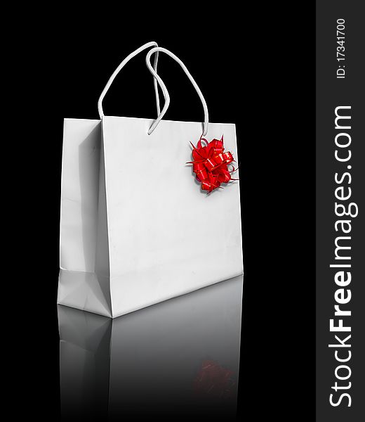 White paper bag and red bow on reflect floor and black background
