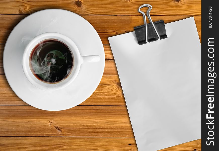 White cup of hot coffee and white paper on wood table