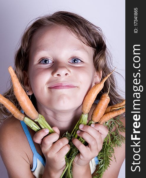 A little girl holding in her hand a beautiful carrots. A little girl holding in her hand a beautiful carrots