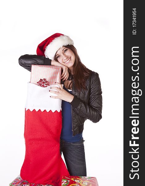 A woman in her Santa hat on with a big smile on her face standing next to a big stocking with presents in it. A woman in her Santa hat on with a big smile on her face standing next to a big stocking with presents in it.