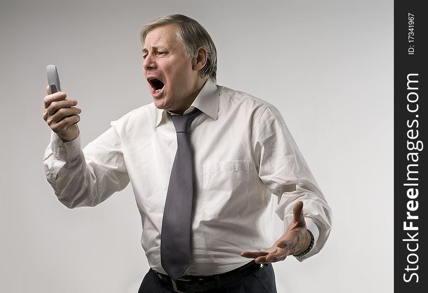 Senior businessman screaming at telephone. Senior businessman screaming at telephone