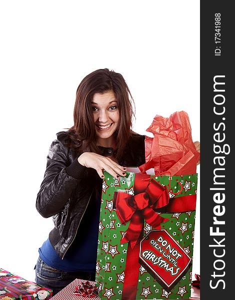 A woman taking a peek into her Christmas bag with an excited expression on her face. A woman taking a peek into her Christmas bag with an excited expression on her face.