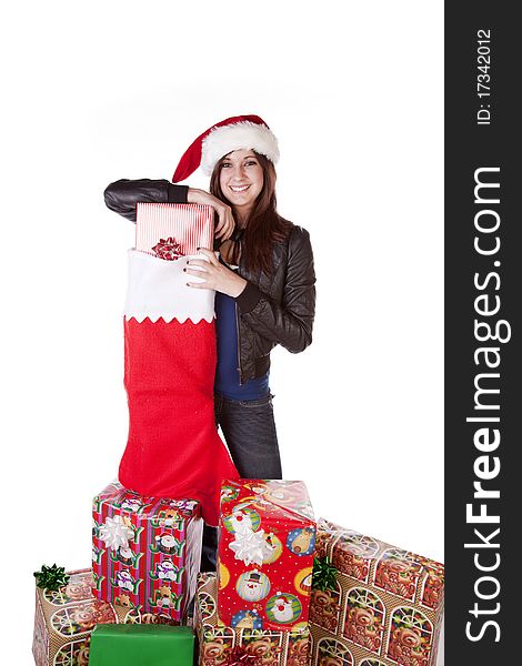 A woman in her Santa hat on with a big smile on her face standing next to a big stocking with presents in it. A woman in her Santa hat on with a big smile on her face standing next to a big stocking with presents in it.