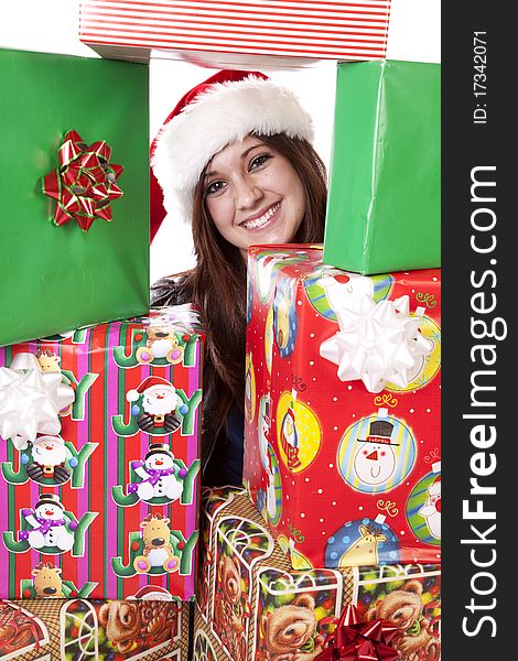 A woman with her face looking through a stack of presents while wearing her Santa hat. A woman with her face looking through a stack of presents while wearing her Santa hat.