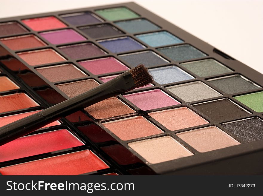 A close-up of a makeup palette with a cosmetic brush.