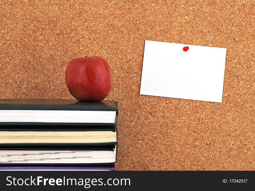 Apple and books. against the background of the inscription cork board