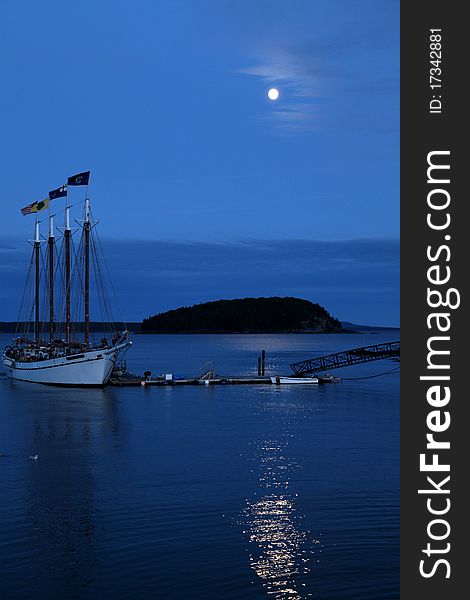 Sail boat anchored in a harbor at full monn with moonlight reflecting from the ocean. Sail boat anchored in a harbor at full monn with moonlight reflecting from the ocean