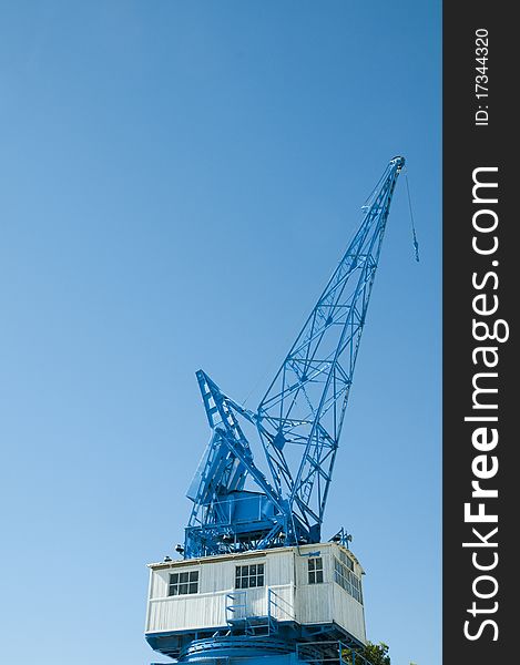 Blue crane against blue skies in dockyard