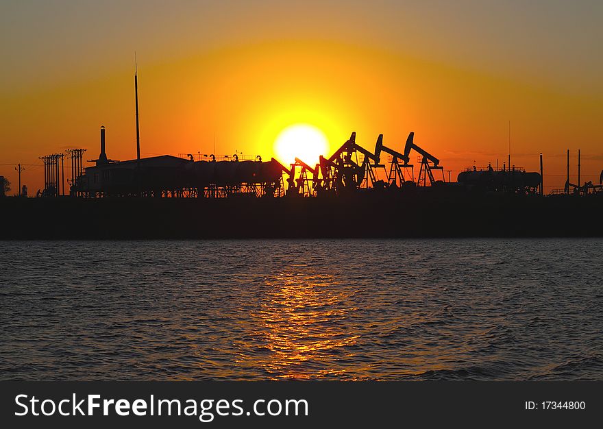 Oil pump silhouette against a bright orange sky. Oil pump silhouette against a bright orange sky