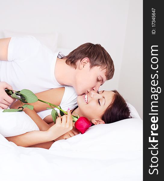 Young man kissing his beautiful girlfriend and giving her a rose. Young man kissing his beautiful girlfriend and giving her a rose