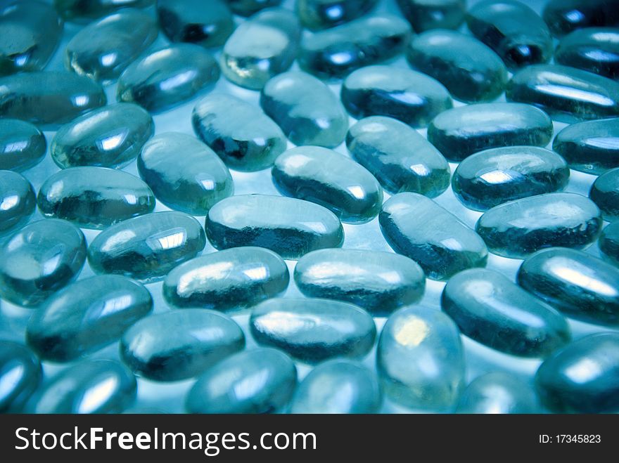 Heap of blue bright glass pebble stones on a turquoise background. Heap of blue bright glass pebble stones on a turquoise background