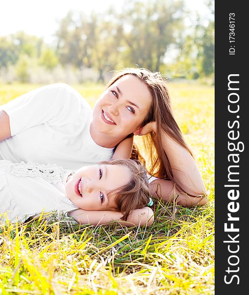 Young mother and her daughter in the park on a sunny autumn day (focus on the child). Young mother and her daughter in the park on a sunny autumn day (focus on the child)