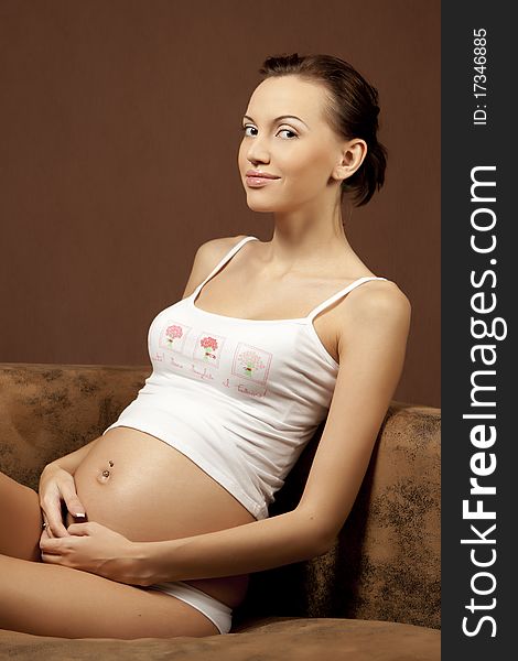 Pregnant woman, sitting on the sofa and smiling