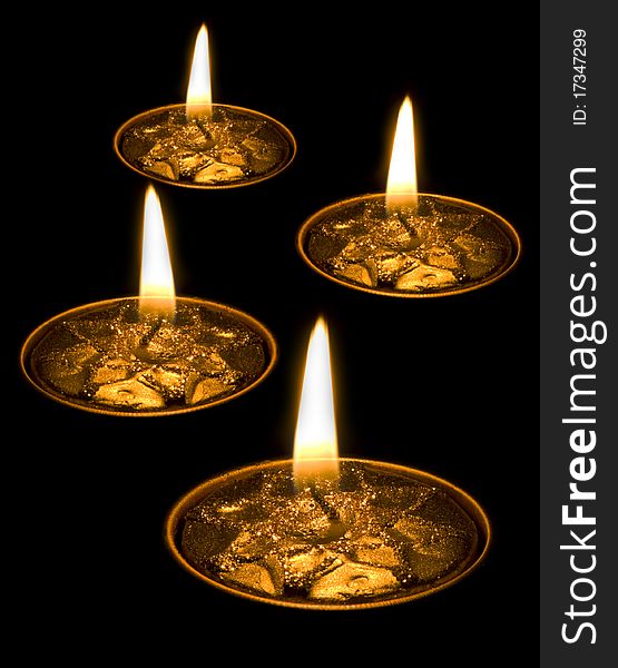 Four burning yellow candles isolated on black background