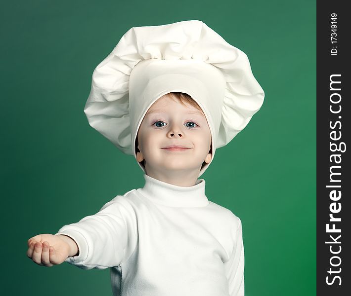 The cheerful little boy in a suit of the cook costs with the lifted hand. The cheerful little boy in a suit of the cook costs with the lifted hand