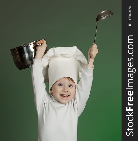 The little boy in a suit of the cook has control over a ladle. The little boy in a suit of the cook has control over a ladle