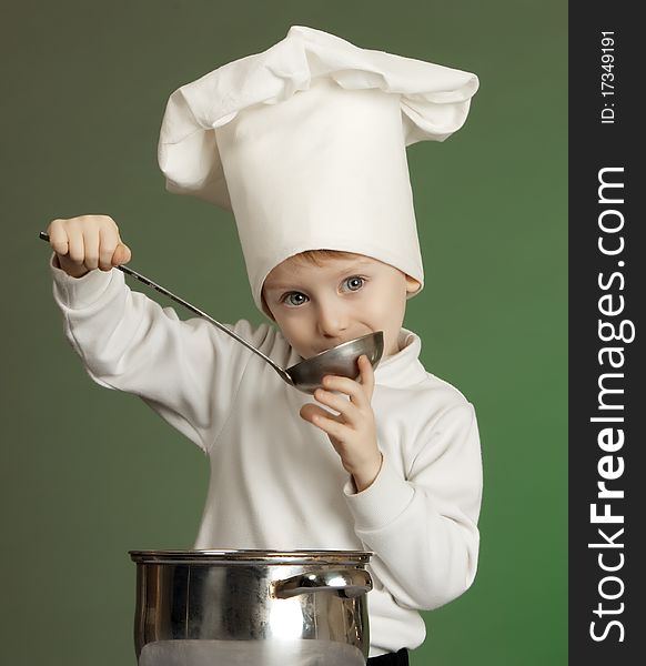 The little boy in a suit of the cook has control over a ladle. The little boy in a suit of the cook has control over a ladle