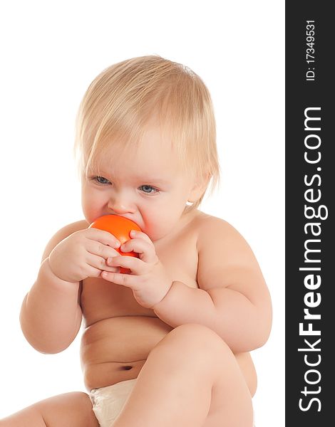 Portrait of angry young sitting baby bitting orange ball