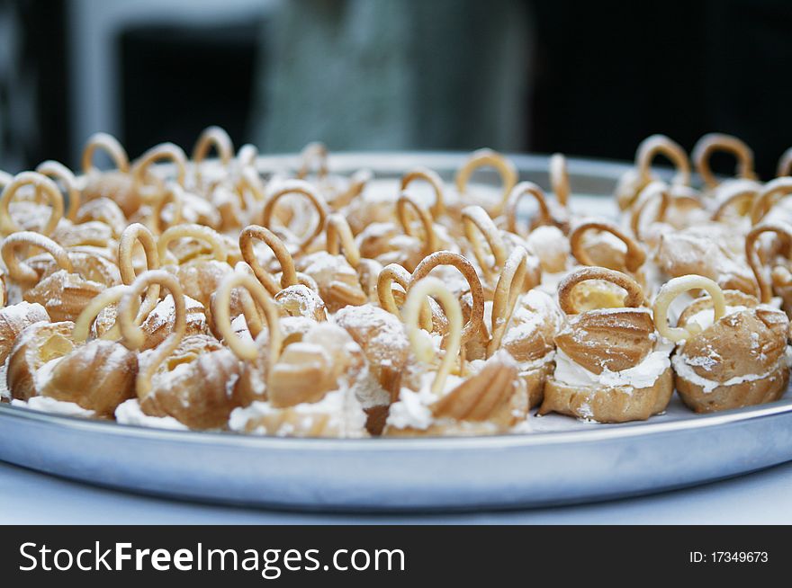 Small delicious wedding cakes with sugar powder on plate.
