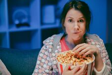 Young Lady Is Watching TV Laughing And Eating Popcorn Having Fun At Home Alone Enjoying Modern Television. Youth Stock Image