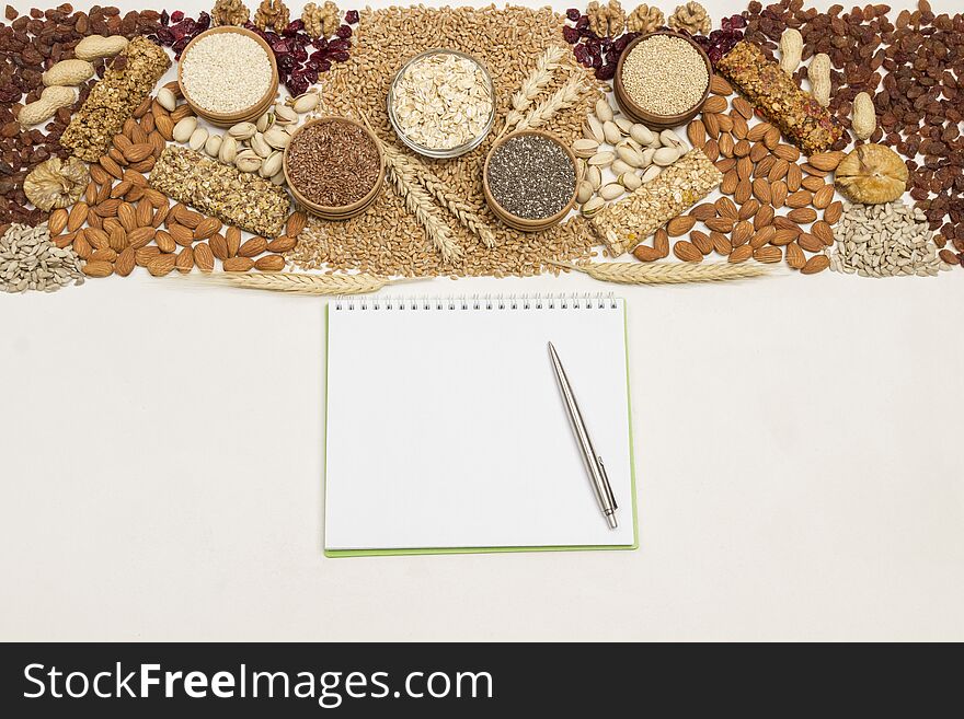 Balanced vegan snack, protein granola bar. Nuts, seeds, cereals notebook, pen on wooden background. Weigh less concept. Flat lay. White background