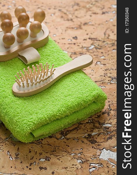 Massager and hairbrush on green towel and all this on corkwood backgound