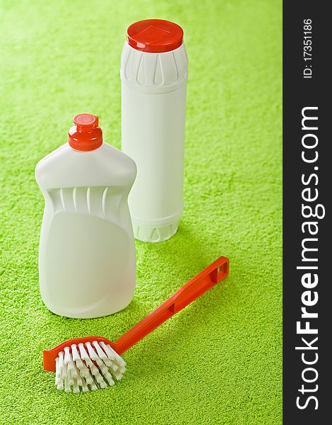 Brush and white bottles on green background of green towel