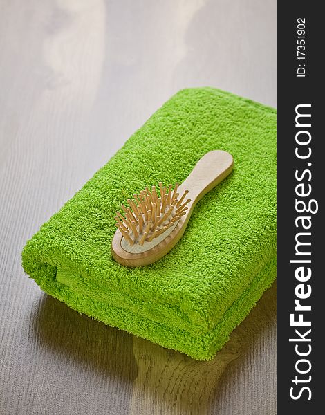 Green towel with hairbrush on wooden background