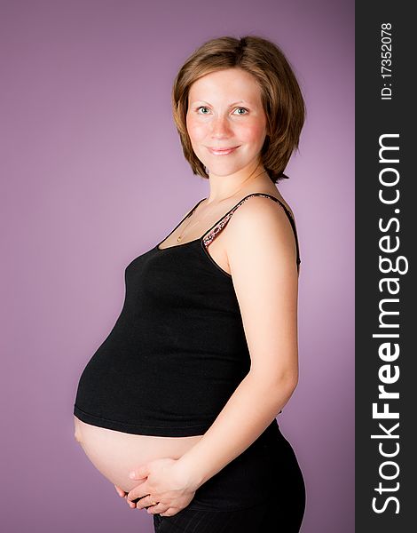 Beautiful pregnant woman staing on purple background