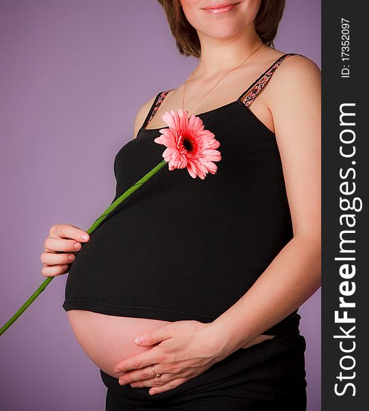 Beautiful pregnant woman  with flower on grey background