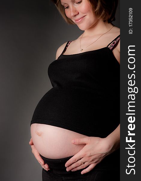 Beautiful pregnant woman staing on grey background