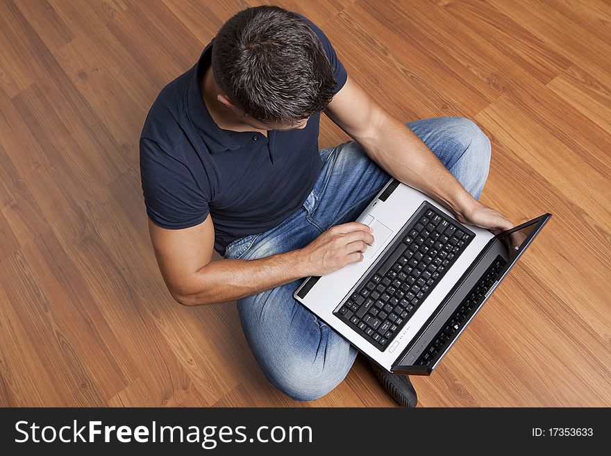 Young man sitting on the floor working on laptop computer at home