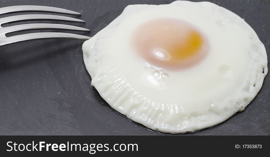 A fied egg in a black plate. A fied egg in a black plate