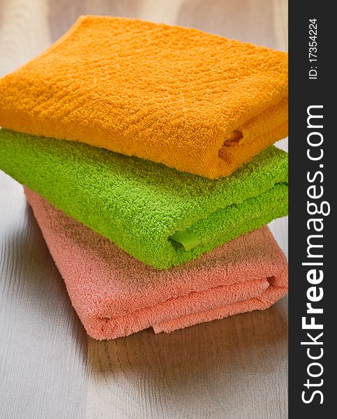 Stack of three colored towels on wooden background