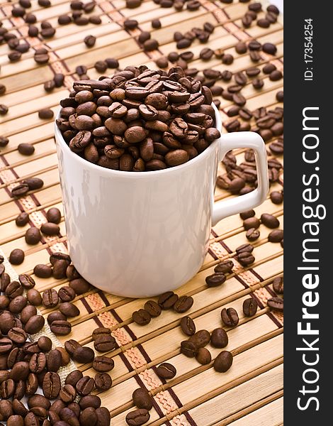 Composition of coffee mug and coffee grain in mug on mat