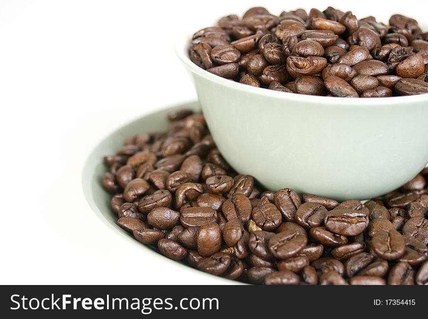 Multiple coffee beans held in a cup and saucer. Multiple coffee beans held in a cup and saucer