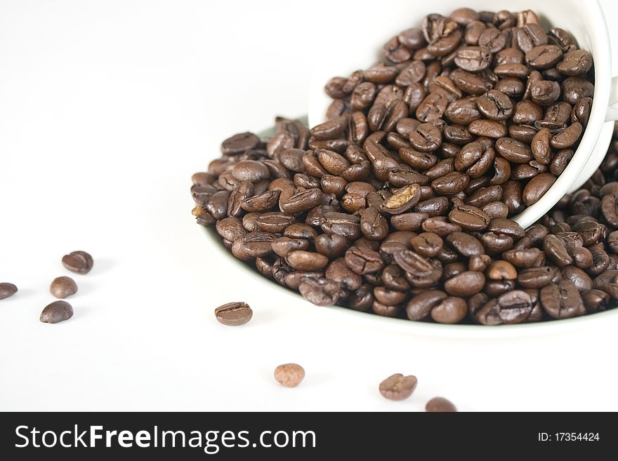 Multiple coffee beans held in a cup and saucer. Multiple coffee beans held in a cup and saucer