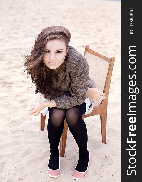 Sexy brunette woman with make up sitting on a chair on beach. Sexy brunette woman with make up sitting on a chair on beach