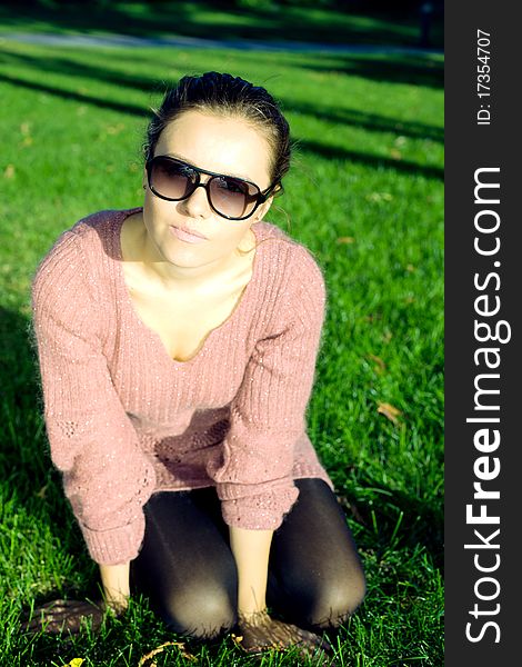 Attractive young woman sitting on green grass