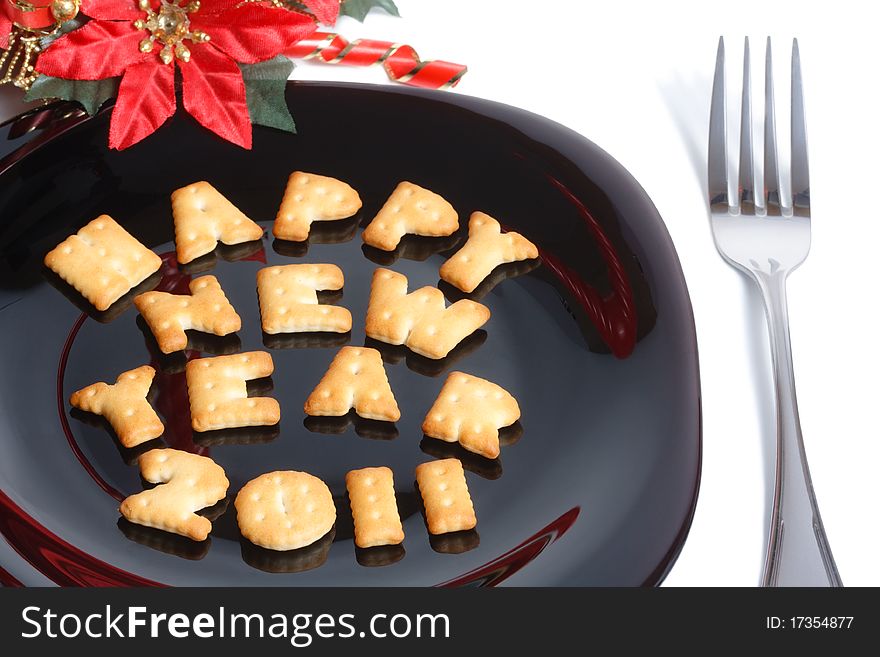 Black plate with character shaped cookies, fork and new year decoration isolated on white. Black plate with character shaped cookies, fork and new year decoration isolated on white