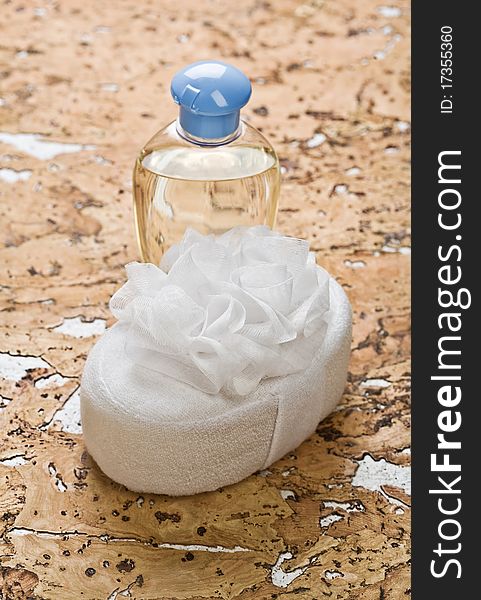 Bath sponge with bottle on a background of the wooden corck
