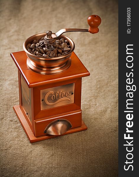 Wooden brown coffee mill with coffee beans on sacking. Wooden brown coffee mill with coffee beans on sacking