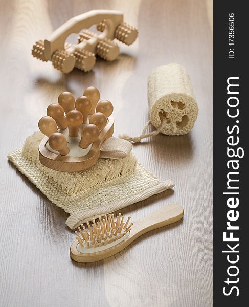 Woodens massager with bath sponge and hairbrush on wooden background