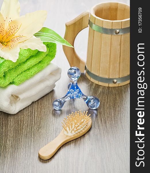 Set of accessories for bathing on wooden background. wooden mug wooden hairbrush plastical massager cooton towels