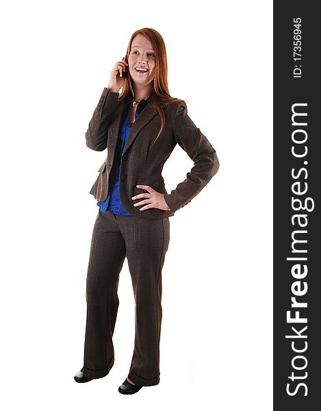 A business woman in a brown suit standing in profile in the studio, with her long red hair and talking on her cell phone for white background. A business woman in a brown suit standing in profile in the studio, with her long red hair and talking on her cell phone for white background.