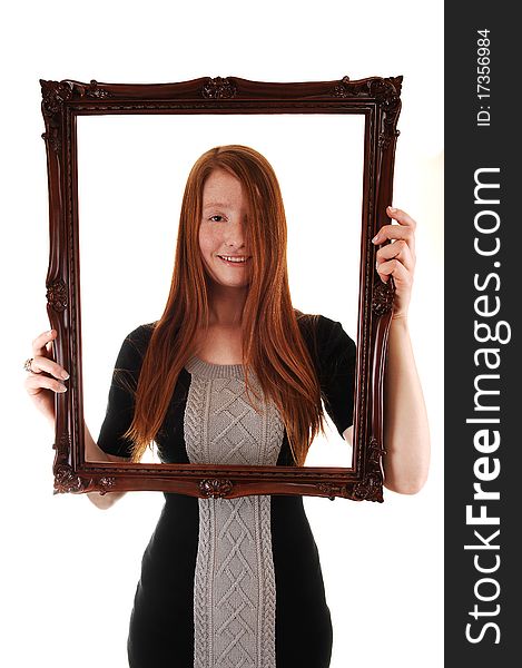 An young woman with long red hair holding a picture frame, in a black dress, with her hair over one eye, on white background. An young woman with long red hair holding a picture frame, in a black dress, with her hair over one eye, on white background.