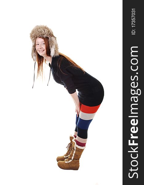 A pretty woman with long red hair in colorful tights, a black sweater and a fur hat and brown boots smiling for a portrait for white background. A pretty woman with long red hair in colorful tights, a black sweater and a fur hat and brown boots smiling for a portrait for white background.