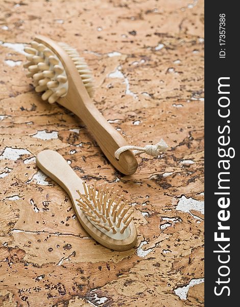 Brown wooden massager and hairbrush on the background of the brown cork wood. Brown wooden massager and hairbrush on the background of the brown cork wood