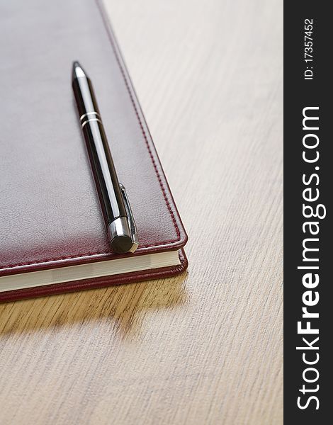 Red notebook with pen on wooden background